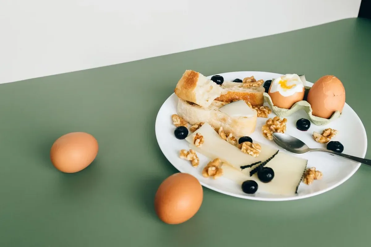 Plate of boiled eggs, cheese, bread, walnuts and blueberries